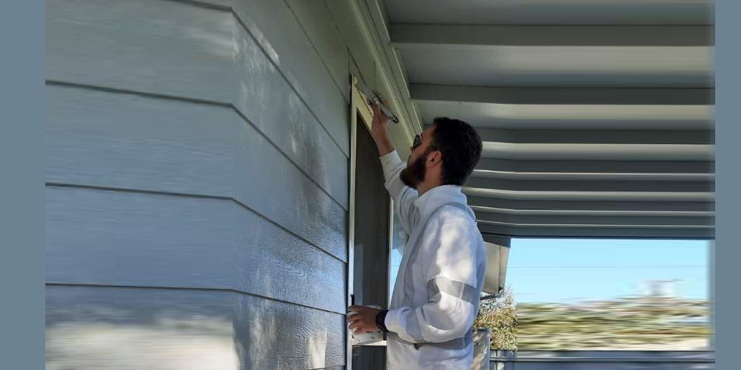 Reece at work painting a grey residential house